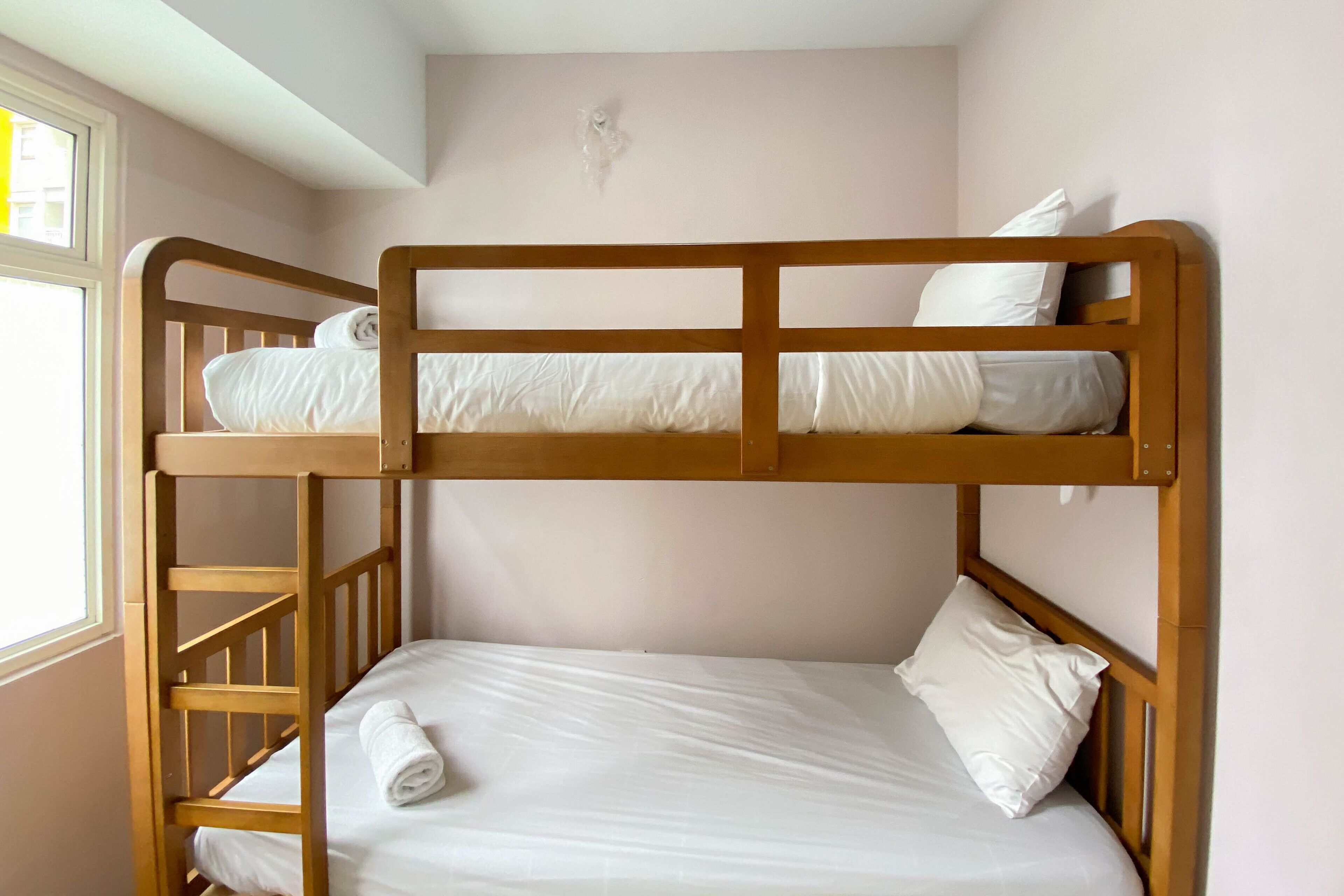 A bunk bed with white bedding and a wooden frame.
