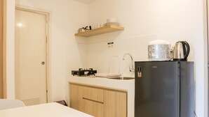 A compact kitchen with a refrigerator, a coffee maker, and a dish rack.