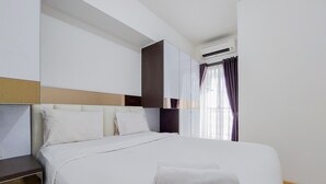 A neatly made bed with white linens, a headboard, and a white towel on the bed. - Warm And Nice 2Br Apartment At M-Town Residence (Gading Serpong)