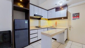 A compact kitchen with white cabinets, a black refrigerator, and a tiled floor. - Warm And Nice 2Br Apartment At M-Town Residence (Gading Serpong)