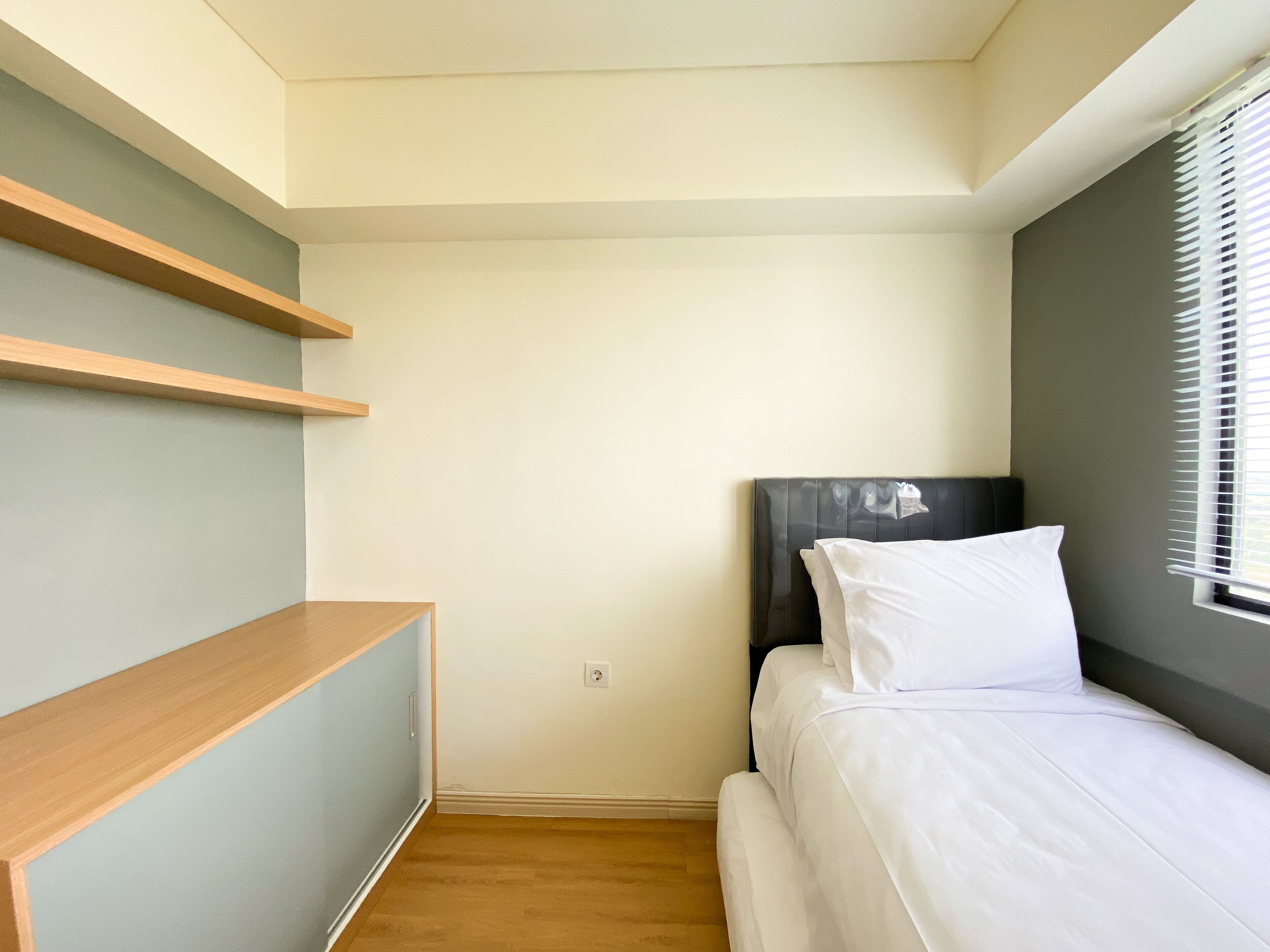 A small, neatly organized bedroom with a bed, a nightstand, and a built-in shelf unit.