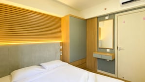 Ett hotellrum med en säng, en sänggavel i trä, en inbyggd garderob, en spegel och en luftkonditioneringsanläggning.