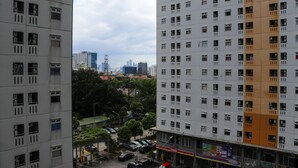 A high-rise building with multiple windows and balconies, surrounded by other buildings and trees.