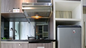 A kitchen with a stainless steel range hood, a built-in gas stove, a refrigerator, and wooden cabinetry.