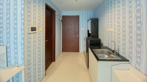 Un couloir étroit, avec une porte au fond, un petit lavabo avec un miroir et un papier peint à motifs.