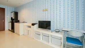 Une chambre dotée d’une kitchenette, d’un téléviseur, de tiroirs de rangement, d’une chaise bleue et d’un panneau « Interdiction de fumer » sur le mur.