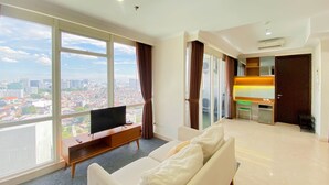 Ein modernes Wohnzimmer mit großem Fenster, einem Flachbildfernseher, einer Couch und einem Essbereich mit Tisch und Stühlen.