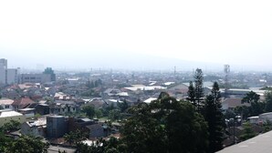 A residential area with houses and buildings, surrounded by trees. - Homey And Cozy Studio Room At Suites @Metro Apartment (Bandung)