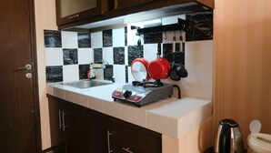 A kitchen with a gas stove, a kettle, and a sink. - Homey And Cozy Studio Room At Suites @Metro Apartment (Bandung)
