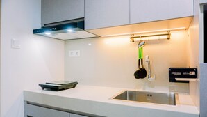 A modern kitchen with a stainless steel sink, a range hood, and a countertop with a scale. - Homey And Simply Look 1Br Bintaro Embarcadero Apartment (South Tangerang)