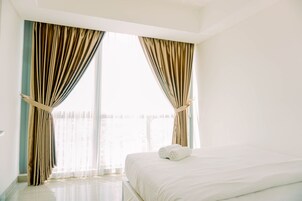Habitación de hotel con una cama grande, cortinas y vistas al exterior.