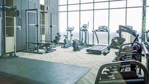 A gym with various exercise equipment, including treadmills, dumbbells, and weight machines. - Spacious And Elegant 2Br At 35Th Floor Hillcrest House Apartment (Curug)