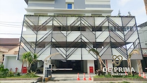 A multi-story building with a modern design, featuring a prominent entrance with a gated driveway, a visible water fountain, and a sign indicating it is an apartment complex.