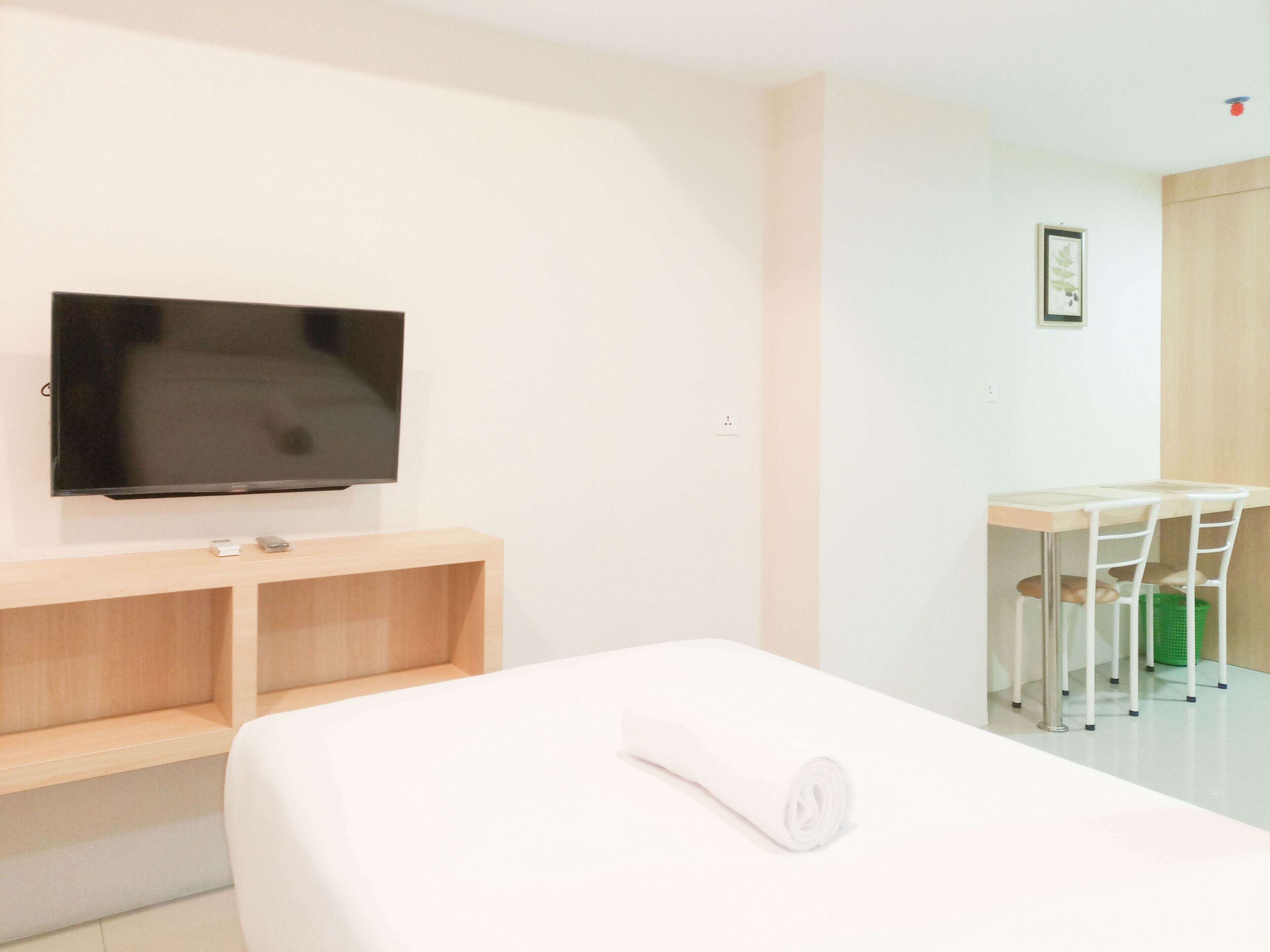 Een hotelkamer met een bed, een bureau, een stoel, een televisie en een klein plankje.