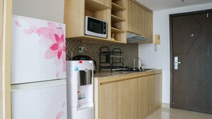 A kitchen with wooden cabinets, a microwave, a refrigerator, and a water dispenser.