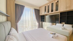 A hotel room with a large bed, a smaller bed, a TV, and a view of the city. - Nice And Elegant 2Br At Menteng Park Apartment (Jakarta)
