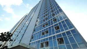 A tall, modern building with a grid of windows and a clear sky. - Nice And Elegant 2Br At Menteng Park Apartment (Jakarta)