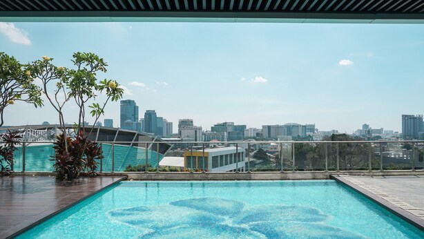 A rooftop pool with a city skyline view, surrounded by glass railings and potted plants. - Nice And Elegant 2Br At Menteng Park Apartment (Jakarta)