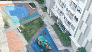 Un edificio residenziale con piscina, area giochi per bambini e giardino.