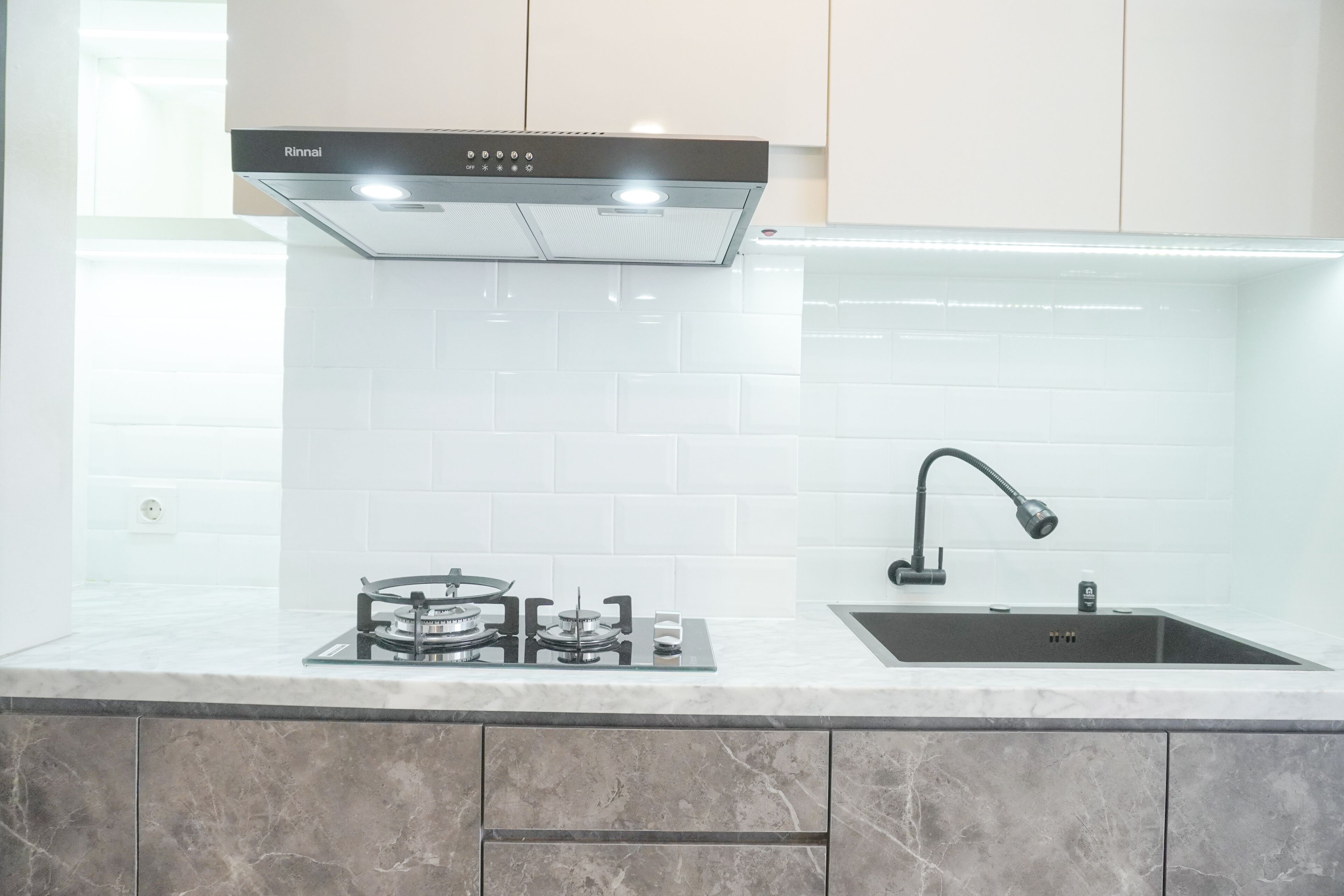 A modern kitchen with a gas stove, a sink, and a range hood.