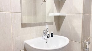 Un bagno con un lavandino bianco, uno specchio e un portaspazzolini.