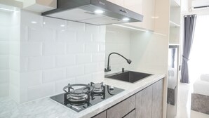 Una cucina moderna con piastrelle bianche a metro, una cappa aspirante nera, un fornello a gas e un lavello nero.