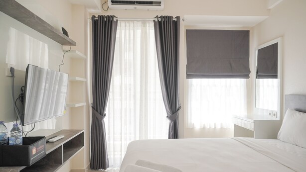 Una camera d'albergo con un letto, una televisione, una scrivania e una finestra con tende.