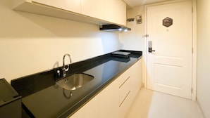 Una cocina moderna con encimera negra, pileta de acero inoxidable y alacenas blancas.