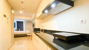 Una cocina moderna con encimera negra, un lavamanos y una estufa empotrada. Hay un pequeño comedor con una silla y una mesa.