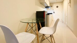 Un rincón comedor pequeño con mesa de vidrio y dos sillas blancas.