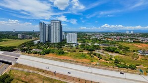A high-rise building complex with multiple floors, surrounded by greenery and a highway in the foreground. - Restful And Best Choice Studio Sky House Bsd Apartment (Pagedangan)