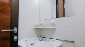 A bathroom with a white sink, a mirror, and a wooden door. - Homey Studio Room At 7Th Floor Gateway Pasteur Apartment (Cimahi)