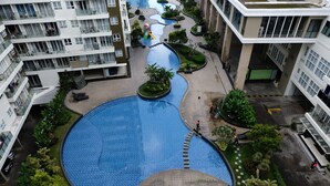A residential building with a central swimming pool surrounded by greenery and a playground. - Homey Studio Room At 7Th Floor Gateway Pasteur Apartment (Cimahi)