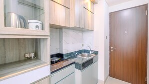 A kitchen with marble countertops, stainless steel appliances, and wooden cabinets. - Cozy Stay Studio At Transpark Cibubur Apartment (Bekasi)