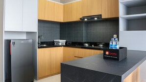 A modern kitchen with wooden cabinets, a black countertop, a built-in oven, and a refrigerator. - Wonderful And Homey 1Br Ciputra International Apartment (Jakarta)