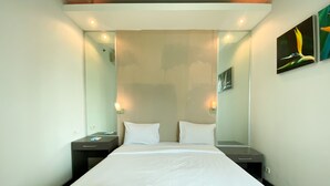 Habitación de hotel con una cama grande, dos mesitas de noche, un espejo adosado a la pared y un cuadro.