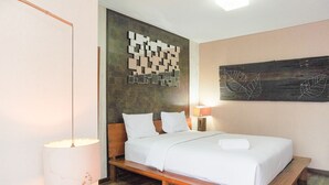 A neatly made bed with white linens, a wooden headboard, and a wall-mounted artwork above it. - Modern And Cozy Stay 1Br At Tamansari Semanggi Apartment (Jakarta)