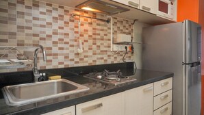 A kitchen with a stainless steel sink, a microwave, a refrigerator, and a tiled backsplash. - Modern And Cozy Stay 1Br At Tamansari Semanggi Apartment (Jakarta)