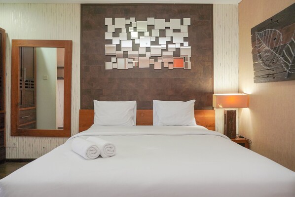 Relax in a stylish room with a comfortable bed, large mirror, and decorative art piece.