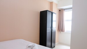 A hotel room with a bed, a black wardrobe, and a window with curtains.