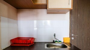 A kitchen with a sink, a red basket, and a yellow container. - Homey 2Br At Suites @Metro Apartment (Bandung)