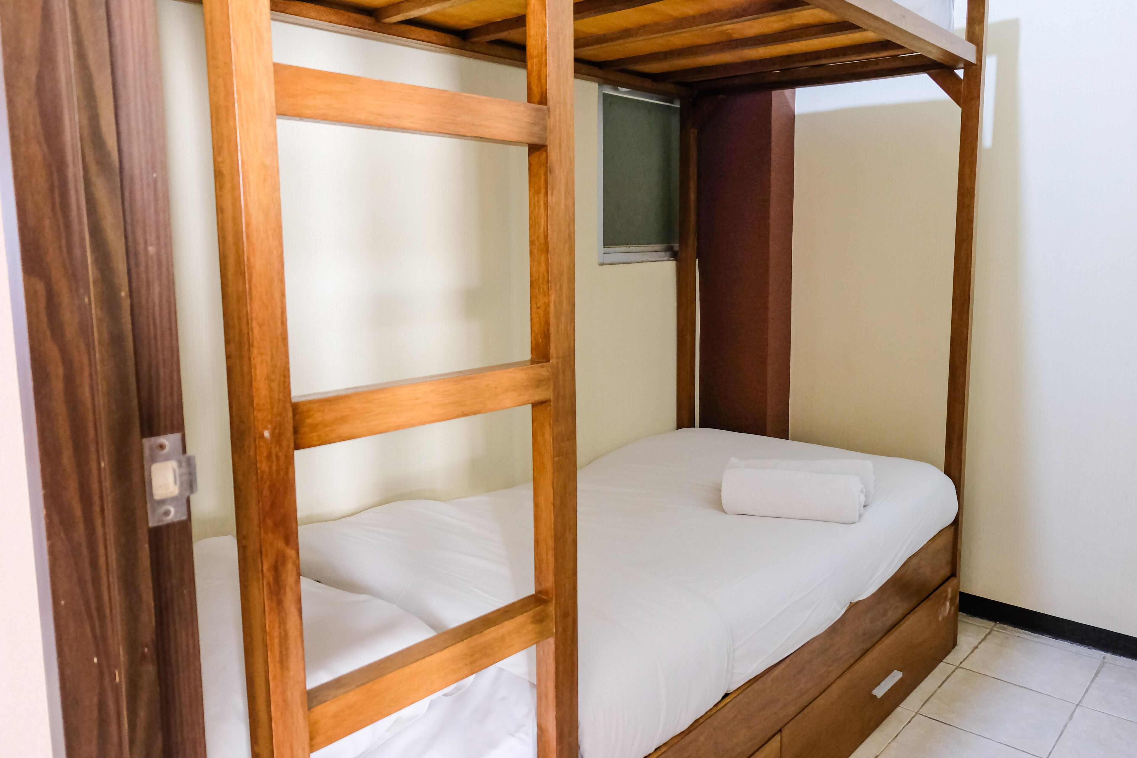 A bunk bed with a wooden frame and white bedding.
