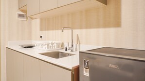 A compact kitchen with a sink, a refrigerator, and a dish rack. - Modern Look 1Br With Golf Island And Sea View Gold Coast Apartment (Jakarta)