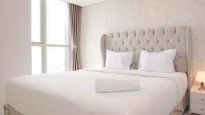 A neatly made bed with a tufted headboard, white bedding, and a bedside table with a lamp. - Modern Look 1Br With Golf Island And Sea View Gold Coast Apartment (Jakarta)