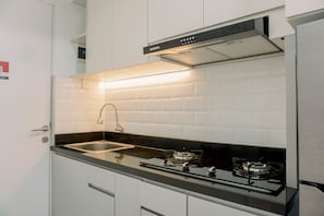 A modern kitchen with white cabinets, a black countertop, a stainless steel sink, and a gas stove.