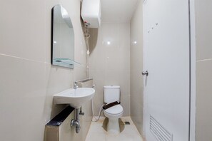 A small, modern bathroom with a white sink, toilet, and mirror. - Restful And Modern 2Br Majestic Point Serpong Apartment (Gading Serpong)