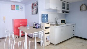 A compact kitchen with white cabinets, a microwave, a water dispenser, and a red cabinet. - Homey And Cozy 1Br Apartment At Braga City Walk (Bandung)