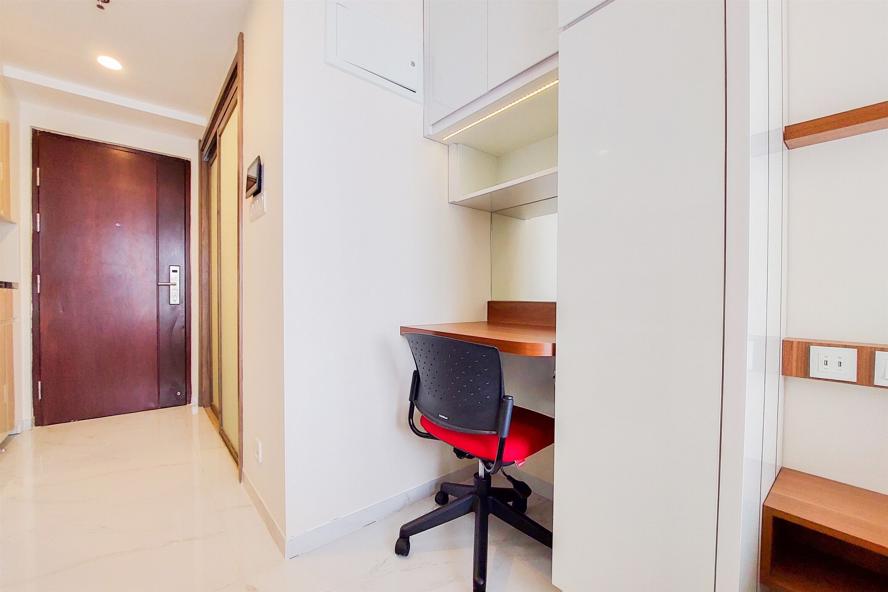A modern office space with a wooden desk, a black office chair, and a white wall.