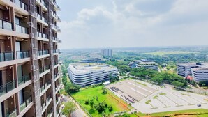 A high-rise building with multiple balconies, a parking lot, and surrounding greenery.