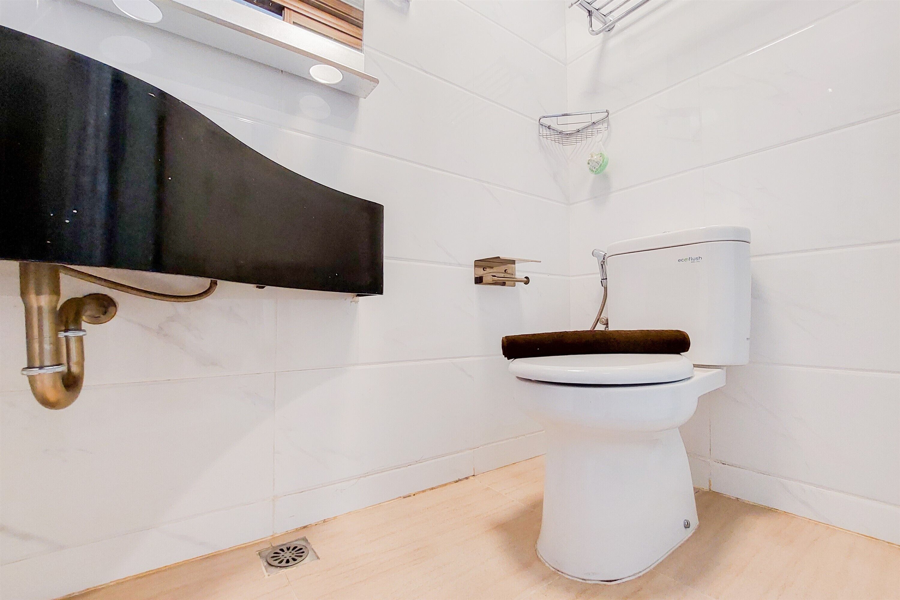 Un baño moderno con inodoro blanco, tocador negro y lavamanos empotrado.